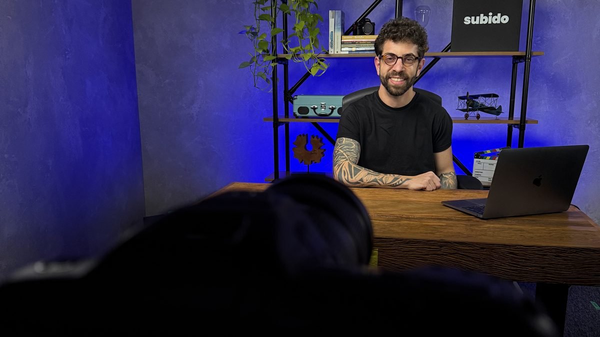 Caio Maia, fundador da Maia Mídia, à mesa com notebook em estúdio de gravação
